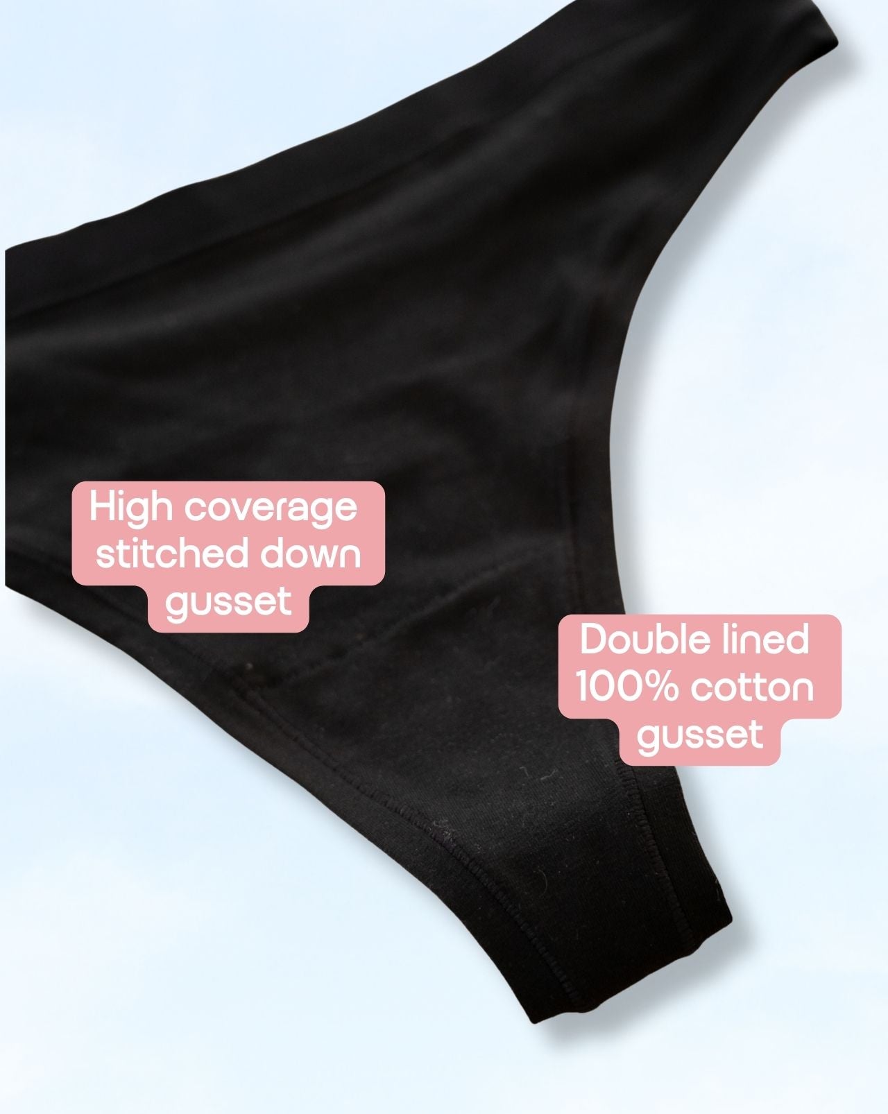 Black underwear gusset detail shot on a light blue background with two pink text callouts reading 'High coverage stitched down gusset' and 'Double lined 100% cotton gusset'.