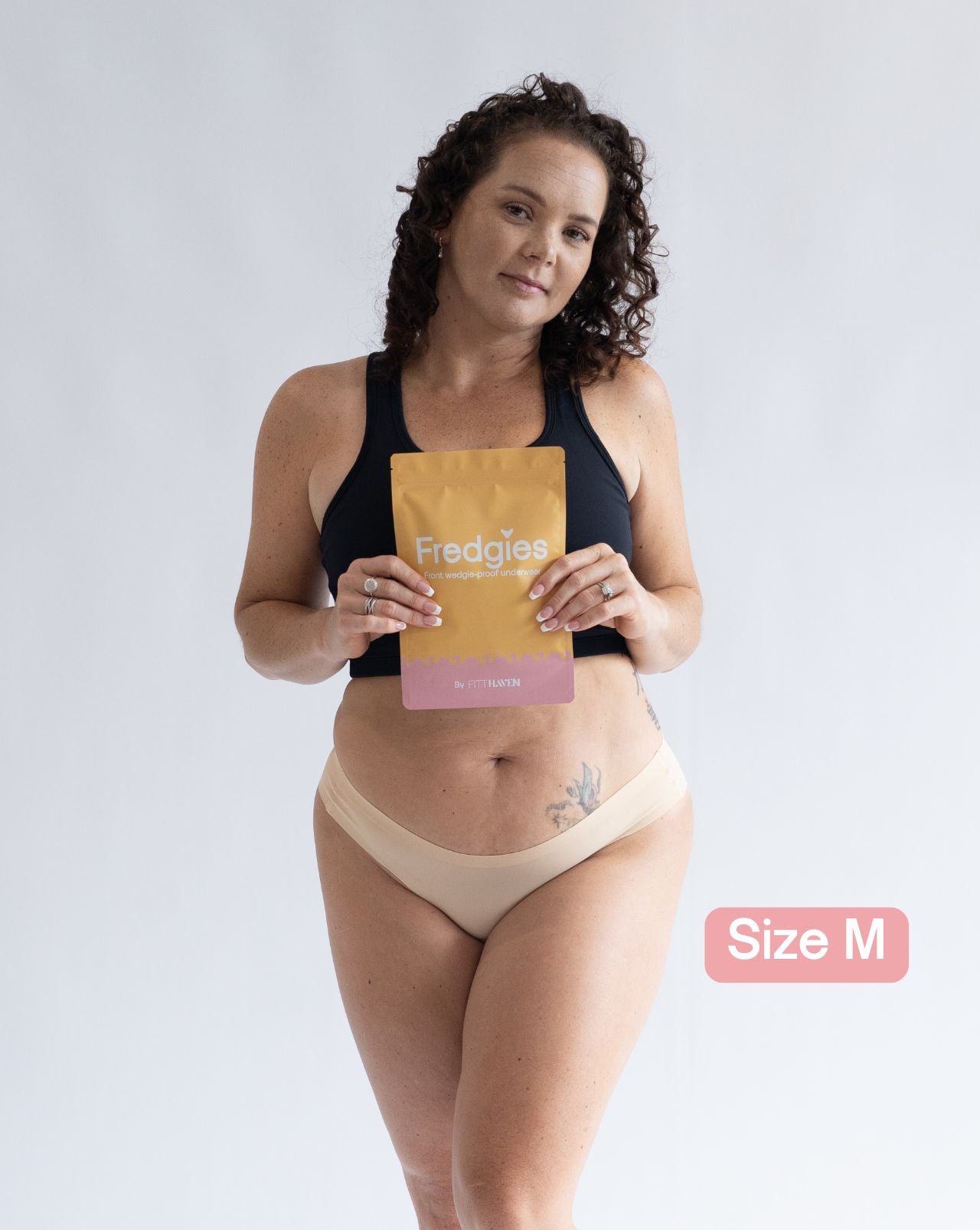 Model holding Fredgies packaging whilst wearing bikini style